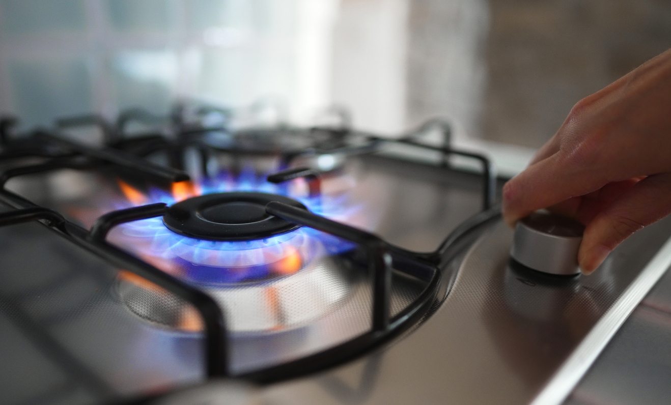 woman-turning-on-the-gas-burner-on-the-stove